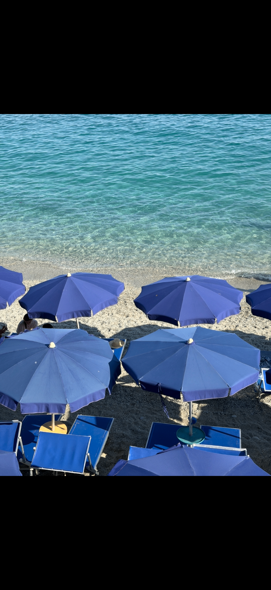 Blue umbrellas on a Ligurian beach near BLUVIA RESIDENCES